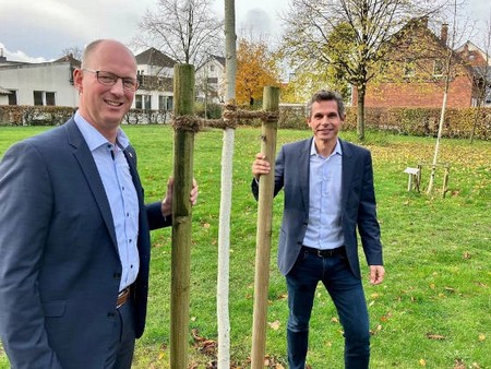Zwei Männer stehen bei einem neu gepflanzten Jungbaum