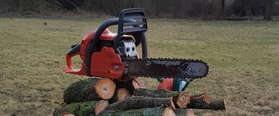 Motorkettensäge liegt auf einem Stapel Brennholz